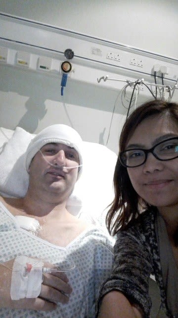 a man in a hospital bed with bandage around his head with a woman supporting him